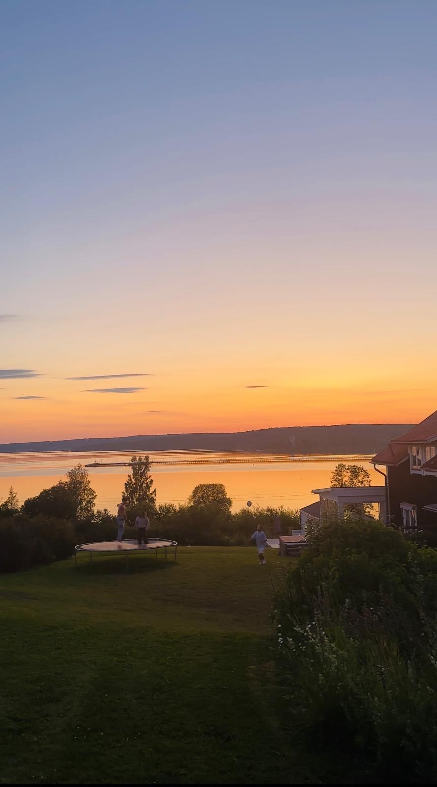 Ljus sommarkväll på gården i Rättvik med studsmatta